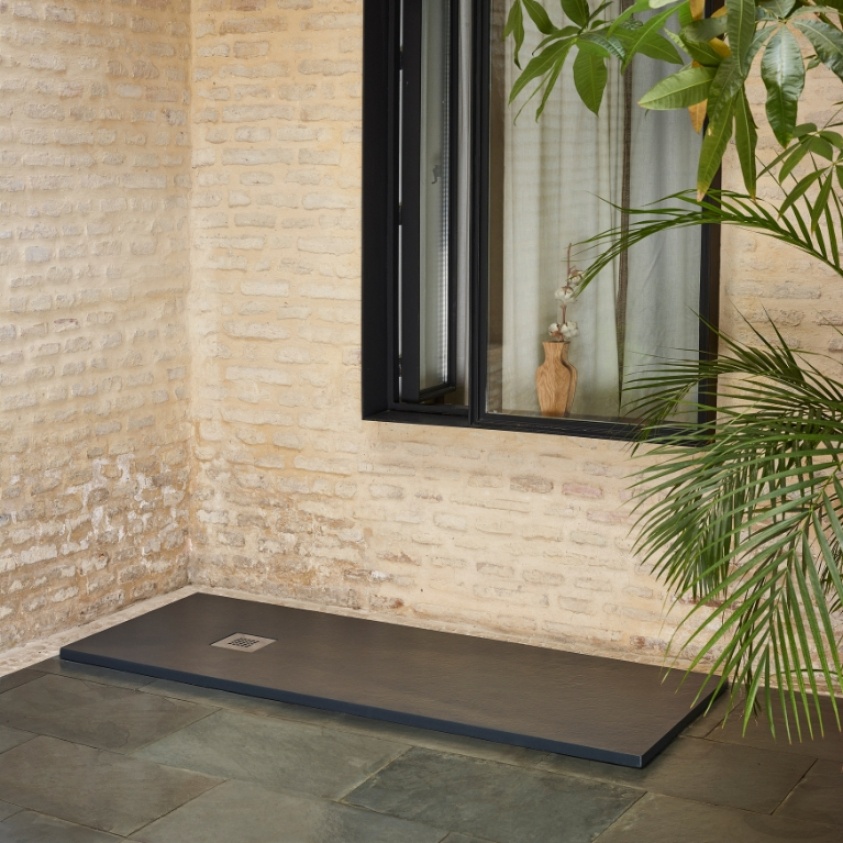 Product Lifestyle image of the Sommer Essenza Graphite Slate 1600mm x 1000mm Shower Tray in a room with brick walls